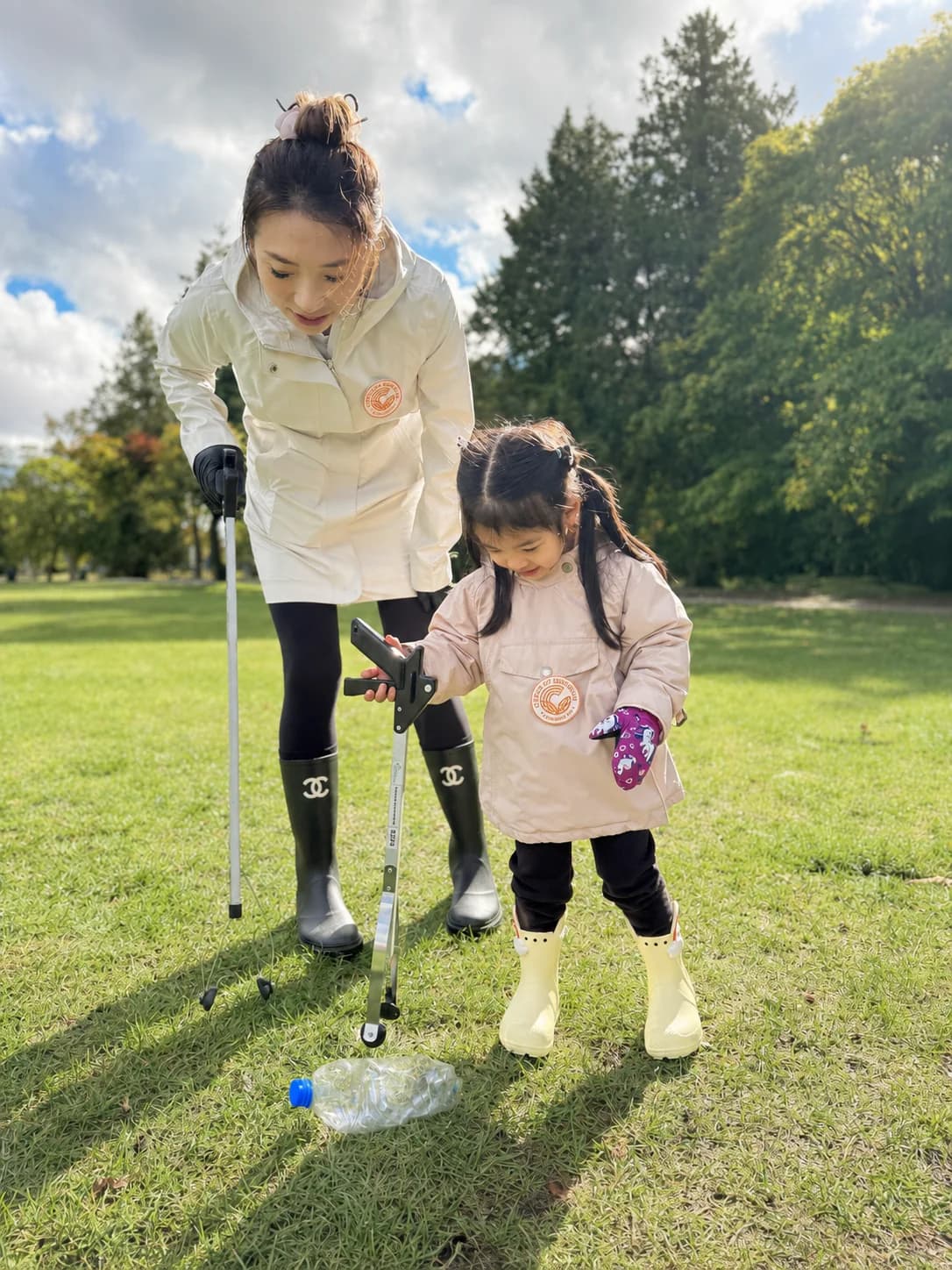 An adult and child picking up litter together in a park
